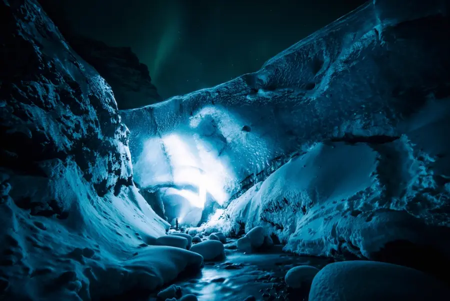 Blár íshellir með ljósi sem skín í gegnum ísinn